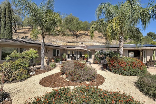9999 Wornom Ave, Sunland, CA 91040 - rear view of property featuring stucco siding, solar panels, and a patio