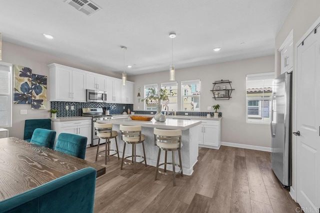 11015 Peyton Way, San Diego, CA 92129 - kitchen with appliances with stainless steel finishes, dark wood-style flooring, light countertops, a kitchen breakfast bar, and white cabinets