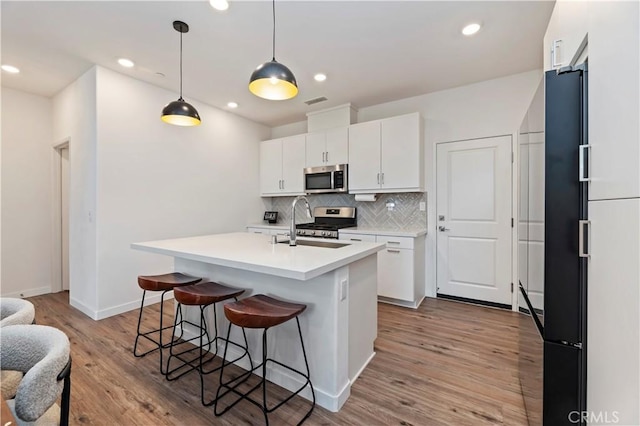 5680 Kate Way Unit 5, Fontana, CA 92336 - kitchen with appliances with stainless steel finishes, decorative backsplash, a breakfast bar, white cabinetry, and light countertops