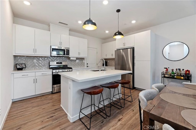 5680 Kate Way Unit 5, Fontana, CA 92336 - kitchen featuring stainless steel appliances, light wood-type flooring, decorative backsplash, light countertops, and a kitchen bar