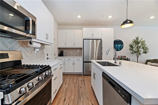 5680 Kate Way Unit 5, Fontana, CA 92336 - kitchen featuring stainless steel appliances, light countertops, light wood finished floors, hanging light fixtures, and white cabinets