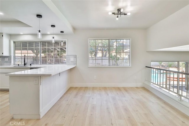 20591 Celtic St, Chatsworth, CA 91311 - kitchen with white cabinets, healthy amount of natural light, light wood-style flooring, and a peninsula