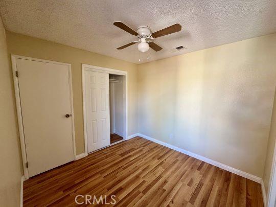 2748 Delmar Ave, Mojave, CA 93501 - unfurnished bedroom with wood finished floors, a closet, a textured ceiling, and ceiling fan