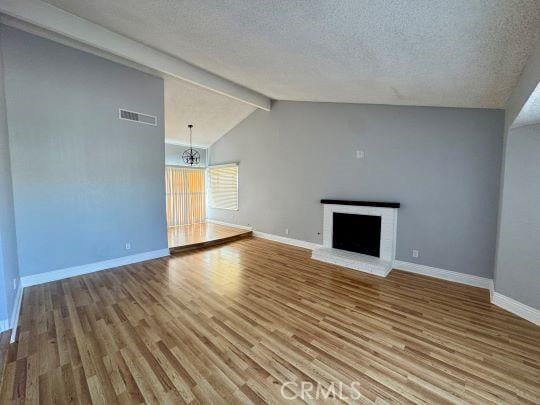 2748 Delmar Ave, Mojave, CA 93501 - unfurnished living room with wood finished floors, a chandelier, a textured ceiling, and a brick fireplace