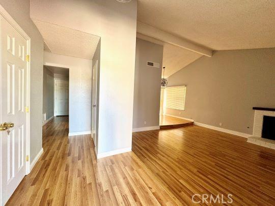 2748 Delmar Ave, Mojave, CA 93501 - unfurnished living room featuring wood finished floors, a fireplace with raised hearth, and a textured ceiling