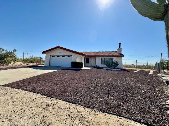 2748 Delmar Ave, Mojave, CA 93501 - ranch-style house featuring concrete driveway, a chimney, a garage, a tile roof, and stucco siding