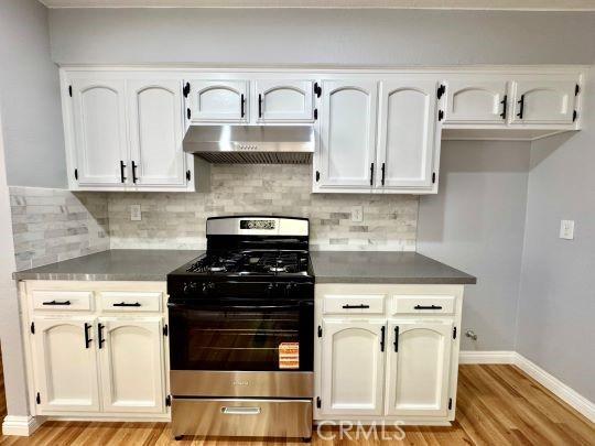 2748 Delmar Ave, Mojave, CA 93501 - kitchen with gas range, range hood, light wood-style flooring, and tasteful backsplash