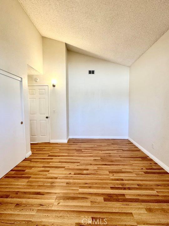 2748 Delmar Ave, Mojave, CA 93501 - empty room with lofted ceiling, a textured ceiling, and light wood finished floors