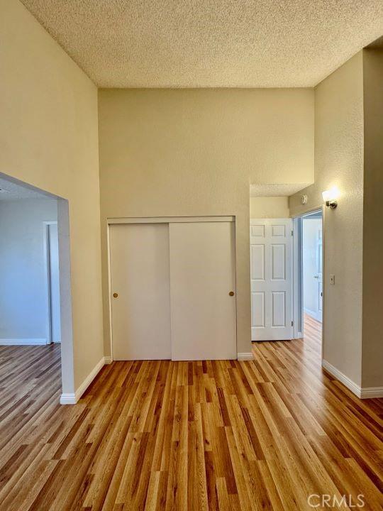 2748 Delmar Ave, Mojave, CA 93501 - unfurnished bedroom with a high ceiling, a closet, wood finished floors, and a textured ceiling