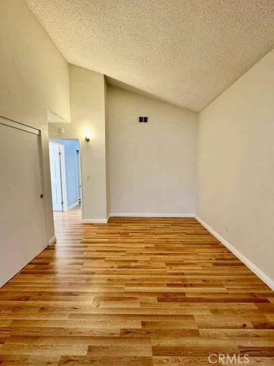 2748 Delmar Ave, Mojave, CA 93501 - spare room featuring lofted ceiling, a textured ceiling, and light wood finished floors