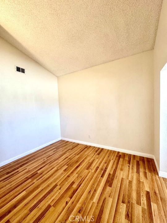 2748 Delmar Ave, Mojave, CA 93501 - unfurnished room with a textured ceiling, light wood finished floors, and lofted ceiling