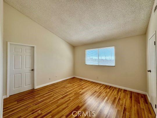 2748 Delmar Ave, Mojave, CA 93501 - unfurnished room featuring a textured ceiling, wood finished floors, and lofted ceiling