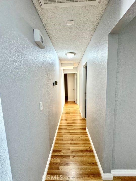 2748 Delmar Ave, Mojave, CA 93501 - corridor featuring light wood finished floors, a textured ceiling, and a textured wall