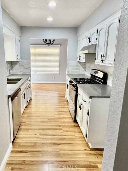2748 Delmar Ave, Mojave, CA 93501 - kitchen featuring appliances with stainless steel finishes, under cabinet range hood, white cabinets, backsplash, and recessed lighting