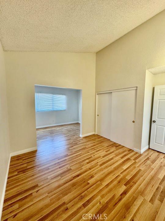 2748 Delmar Ave, Mojave, CA 93501 - empty room featuring wood finished floors, a textured ceiling, and vaulted ceiling