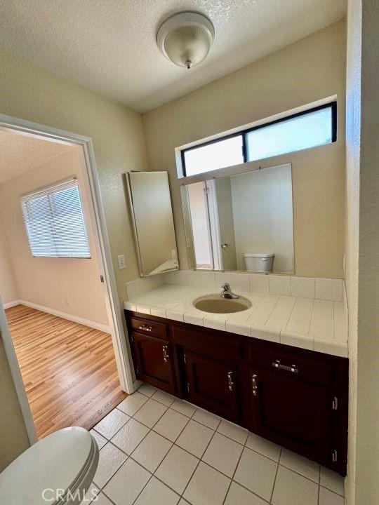 2748 Delmar Ave, Mojave, CA 93501 - bathroom featuring vanity, plenty of natural light, a textured ceiling, and tile patterned flooring
