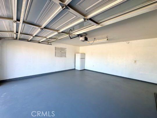 2748 Delmar Ave, Mojave, CA 93501 - garage with freestanding refrigerator and a garage door opener