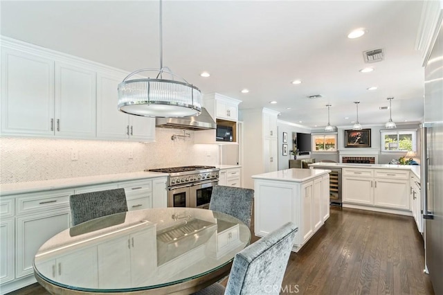 10411 Windtree Dr, Los Angeles, CA 90077 - kitchen with range with two ovens, white cabinets, decorative backsplash, decorative light fixtures, and a kitchen island