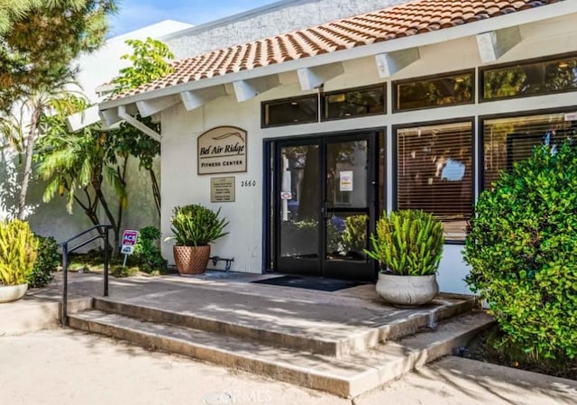 10411 Windtree Dr, Los Angeles, CA 90077 - view of exterior entry featuring french doors, a tile roof, and stucco siding