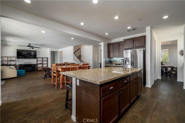 18094 Olivenhain Dr, Riverside, CA 92508 - kitchen with a ceiling fan, dark wood-type flooring, a kitchen island, light stone countertops, and dark brown cabinetry