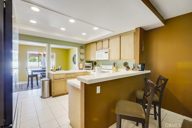 24412 Verena Ct, Mission Viejo, CA 92691 - kitchen with white appliances, a peninsula, recessed lighting, a tray ceiling, and tile counters
