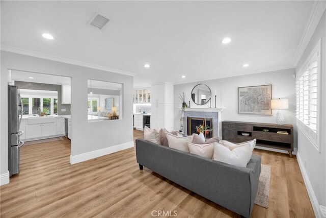 12012 Paseo Bonita, Los Alamitos, CA 90720 - living area with crown molding, a premium fireplace, light wood-style flooring, and recessed lighting