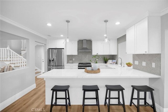 12012 Paseo Bonita, Los Alamitos, CA 90720 - kitchen featuring stainless steel appliances, wall chimney range hood, a peninsula, white cabinetry, and backsplash