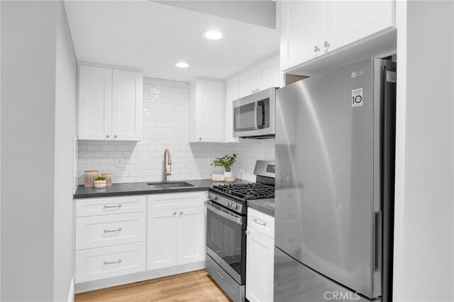 12012 Paseo Bonita, Los Alamitos, CA 90720 - kitchen featuring appliances with stainless steel finishes, dark countertops, white cabinets, light wood-style flooring, and backsplash