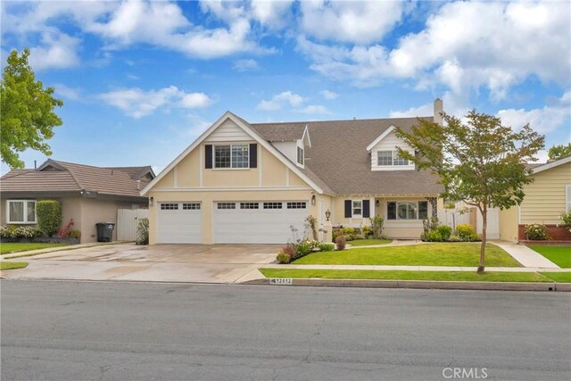 12012 Paseo Bonita, Los Alamitos, CA 90720 - tudor house featuring driveway, a front yard, an attached garage, stucco siding, and a chimney