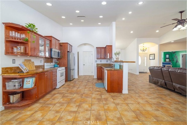 9600 S Loop Blvd, California City, CA 93505 - kitchen with white gas stove, arched walkways, stainless steel microwave, open floor plan, and freestanding refrigerator