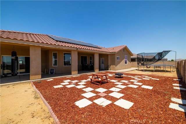 9600 S Loop Blvd, California City, CA 93505 - rear view of house with a trampoline, stucco siding, a fire pit, and roof mounted solar panels