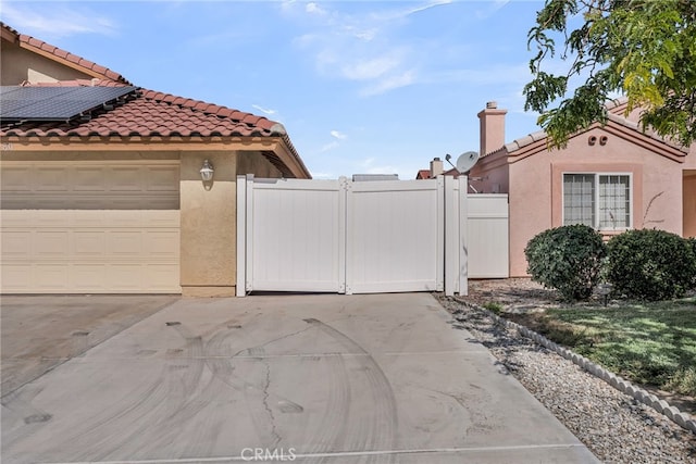 13180 Meteor Dr, Victorville, CA 92395 - view of side of home with a gate, stucco siding, a tile roof, solar panels, and driveway