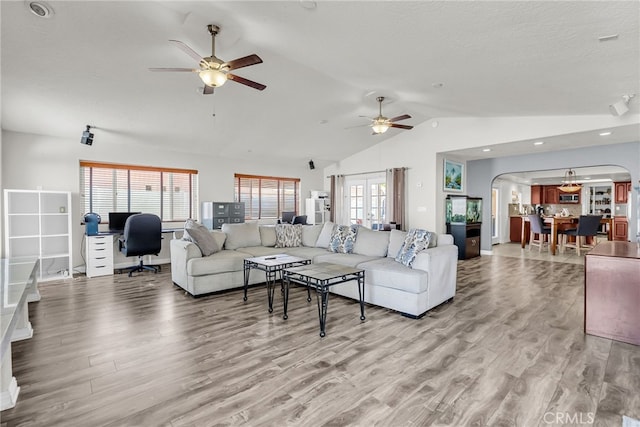 13180 Meteor Dr, Victorville, CA 92395 - living area featuring arched walkways, vaulted ceiling, ceiling fan, light wood-style floors, and healthy amount of natural light