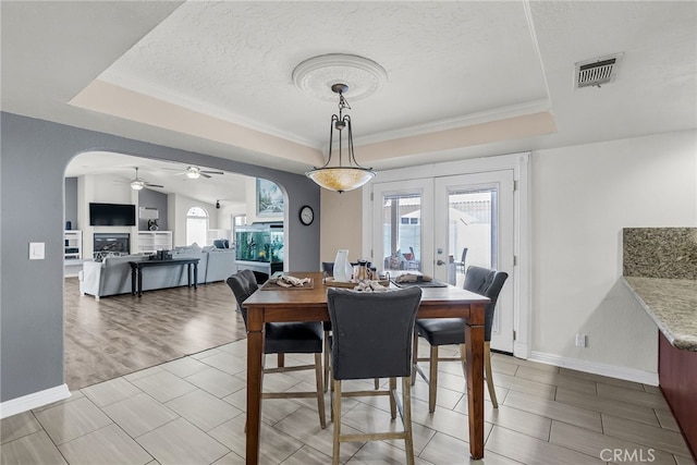 13180 Meteor Dr, Victorville, CA 92395 - dining area featuring a raised ceiling, arched walkways, a textured ceiling, french doors, and ceiling fan