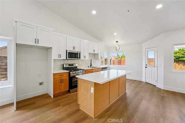 7652 Plumaria, Fontana, CA 92336 - kitchen featuring stainless steel appliances, a center island, lofted ceiling, backsplash, and light countertops