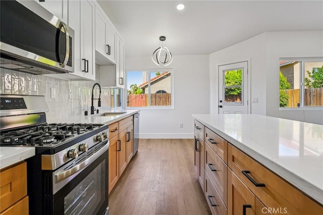 7652 Plumaria, Fontana, CA 92336 - kitchen featuring stainless steel appliances, light wood-style flooring, decorative backsplash, light stone countertops, and brown cabinetry