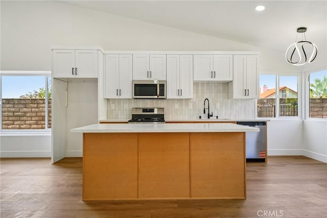 7652 Plumaria, Fontana, CA 92336 - kitchen featuring stainless steel appliances, lofted ceiling, a kitchen island, light countertops, and decorative backsplash