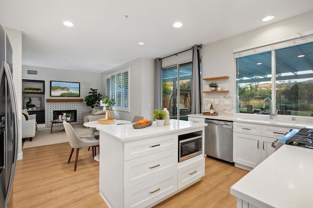 3071 Sprucewood Ln, Escondido, CA 92027 - kitchen with stainless steel appliances, light wood finished floors, a tiled fireplace, light countertops, and recessed lighting