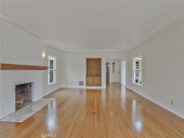 1017 Cordova Ave, Glendale, CA 91207 - unfurnished living room featuring healthy amount of natural light, built in shelves, light wood finished floors, and a brick fireplace