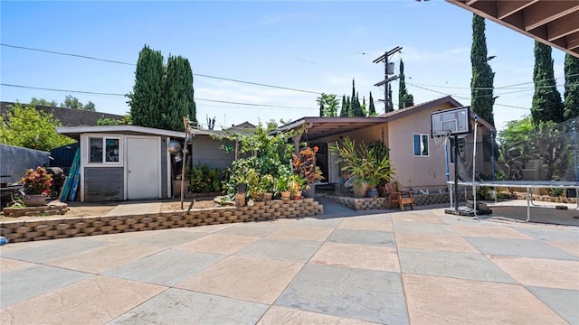 14658 Maclay St, San Fernando, CA 91345 - view of front of house with a trampoline, a patio area, a storage shed, and stucco siding