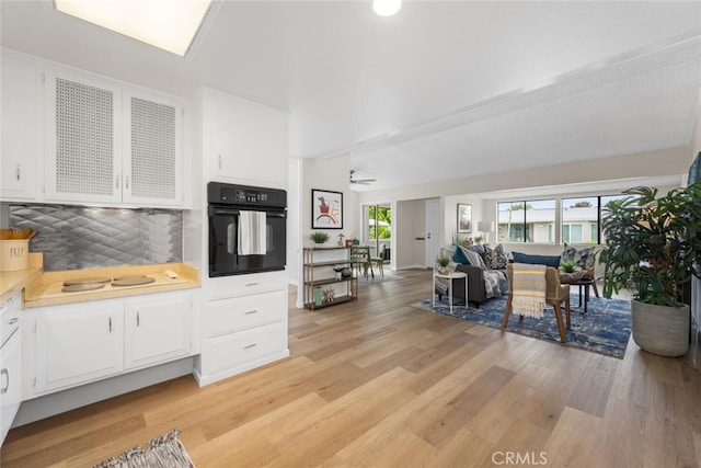 1661 Monterey Rd Unit 16G, Seal Beach, CA 90740 - kitchen featuring oven, white cabinets, light wood-type flooring, and backsplash