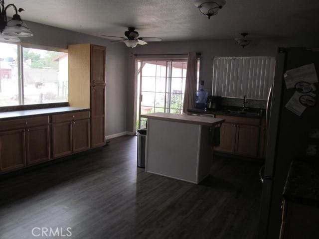 14537 Yucca St, Hesperia, CA 92345 - kitchen featuring a ceiling fan, stainless steel refrigerator with ice dispenser, a kitchen island, dark wood-style flooring, and decorative light fixtures