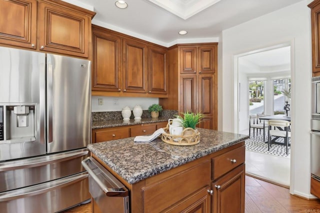 3309 Caminito Cabo Viejo, Del Mar, CA 92014 - kitchen with stainless steel fridge, brown cabinets, recessed lighting, dark stone countertops, and a center island