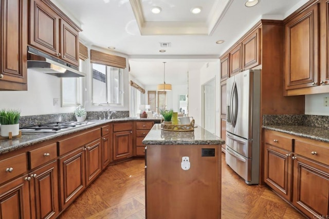3309 Caminito Cabo Viejo, Del Mar, CA 92014 - kitchen featuring under cabinet range hood, stainless steel appliances, a kitchen island, a raised ceiling, and brown cabinetry