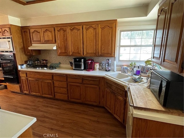 13431 Olympus Dr, Westminster, CA 92683 - kitchen with black appliances, brown cabinets, under cabinet range hood, and a warming drawer