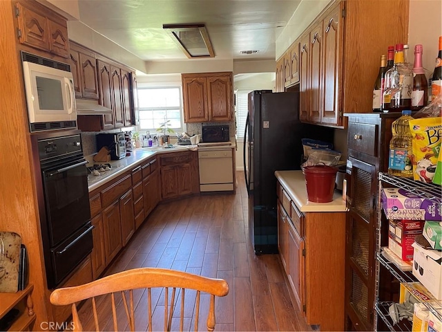 13431 Olympus Dr, Westminster, CA 92683 - kitchen with black appliances, hardwood / wood-style flooring, a warming drawer, light countertops, and brown cabinetry