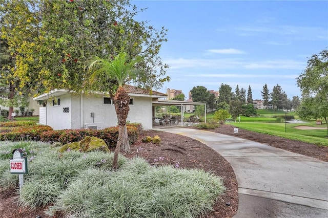 3486 Bahia Blanca W Unit 3F, Laguna Woods, CA 92637 - view of home's exterior featuring stucco siding, driveway, a carport, and a yard