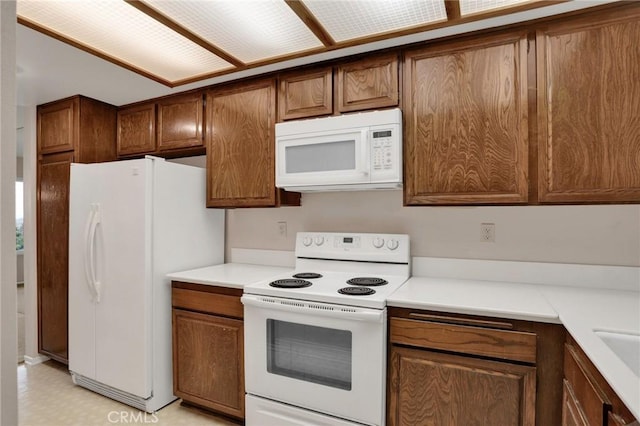 3486 Bahia Blanca W Unit 3F, Laguna Woods, CA 92637 - kitchen with white appliances, light flooring, brown cabinets, and light countertops