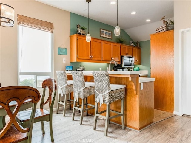 271 Vista Del Mar Unit 1, San Simeon, CA 93452 - kitchen with stainless steel microwave, light countertops, light wood finished floors, vaulted ceiling, and a peninsula