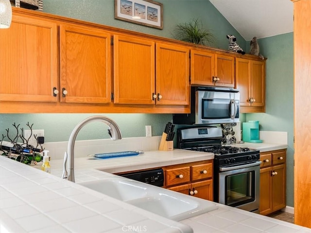 271 Vista Del Mar Unit 1, San Simeon, CA 93452 - kitchen featuring stainless steel appliances, tile countertops, brown cabinetry, and lofted ceiling